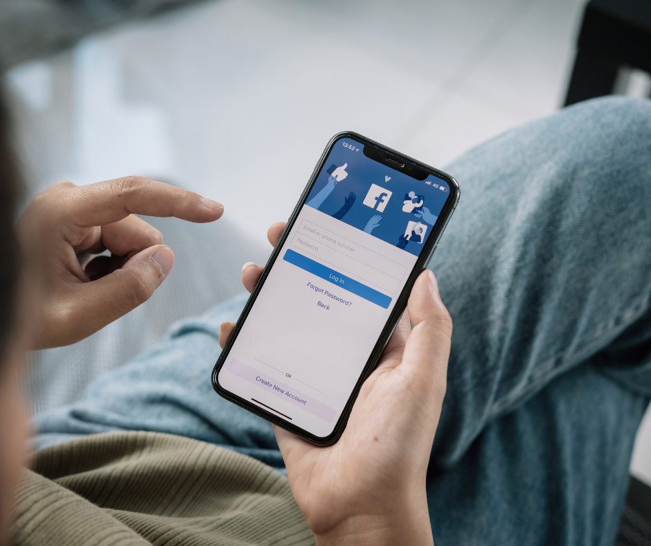 Someone holding a phone logging on to Facebook